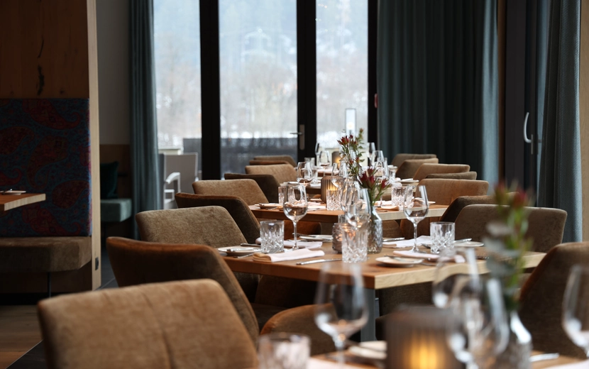 Elegant gedeckte Restauranttische an großen Fenstern im Metzgerwirt Zillertal.