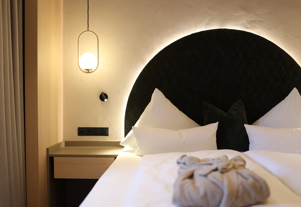 Detailaufnahme des Doppelbetts mit rundem Kopfteil und warmem Licht im Doppelzimmer Lifestyle Komfort.